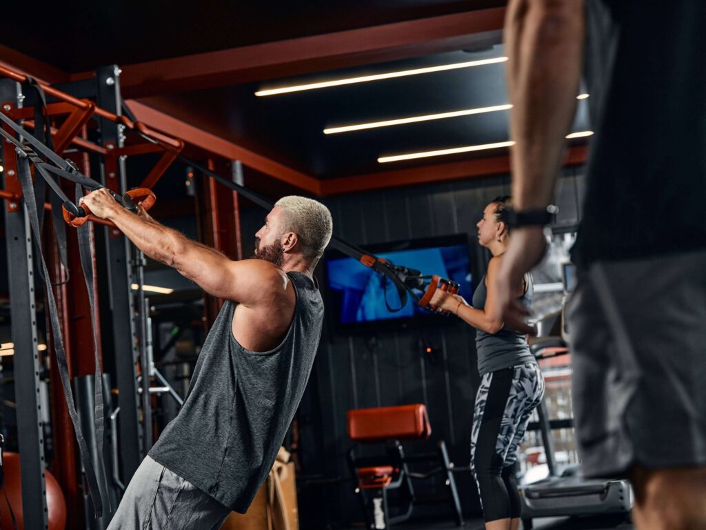 Two gym members exercising with ropes