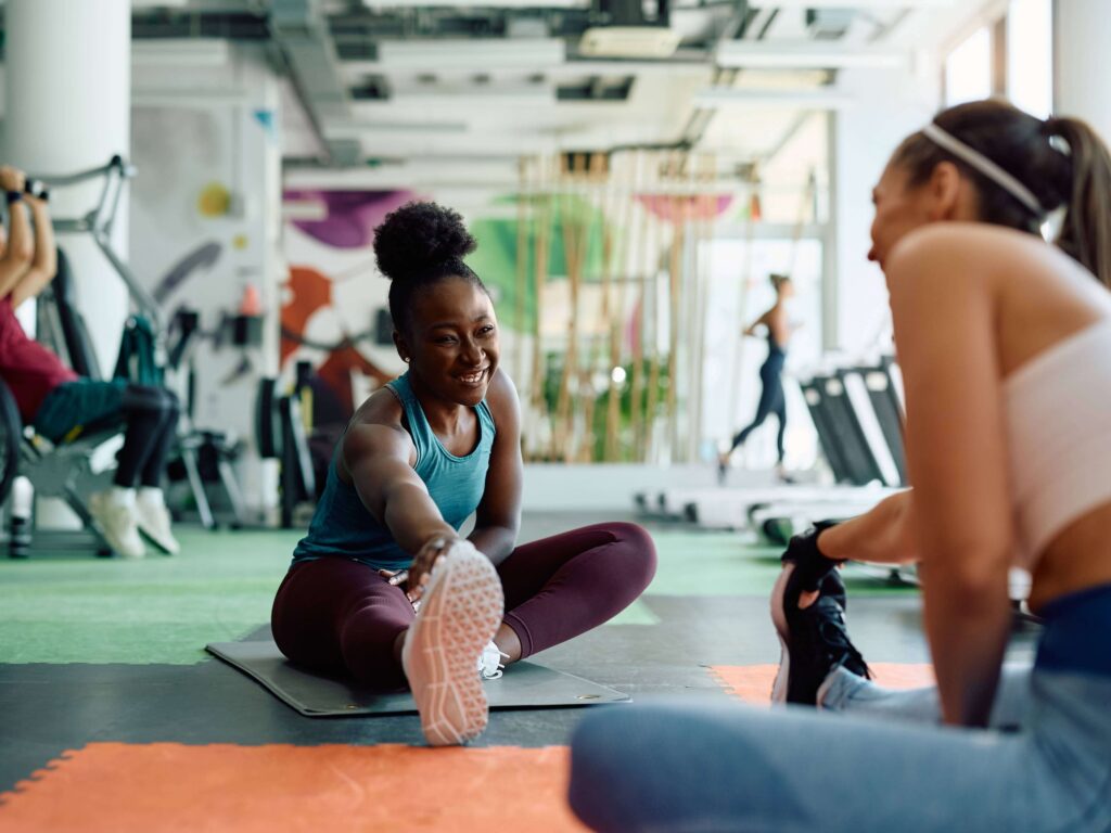 Two friends smiling at each other while stretching