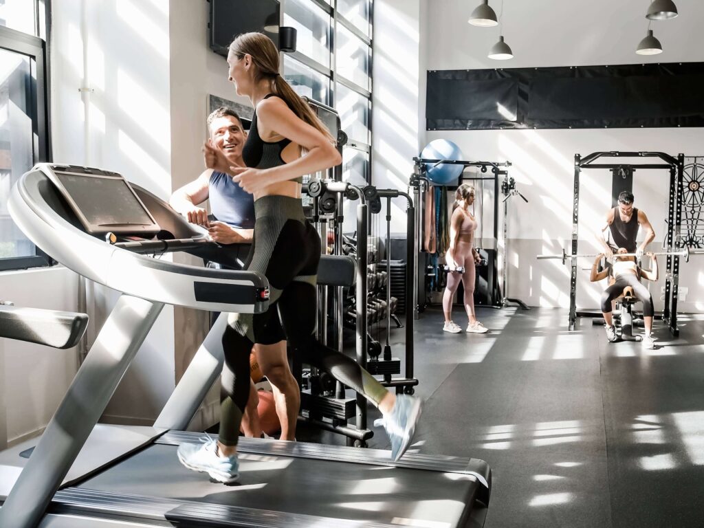 Trainer supporting woman running on treadmill